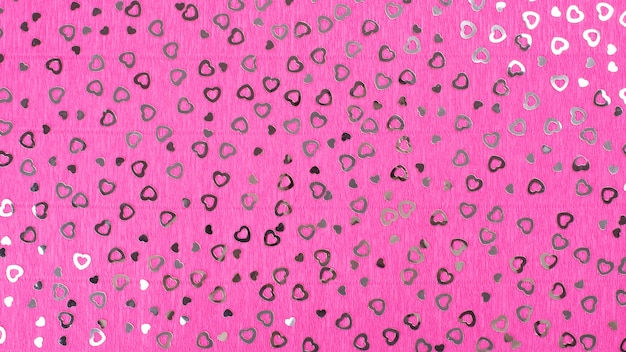 Fondo rosado brillante del papel de crespón con las lentejuelas de los corazones.