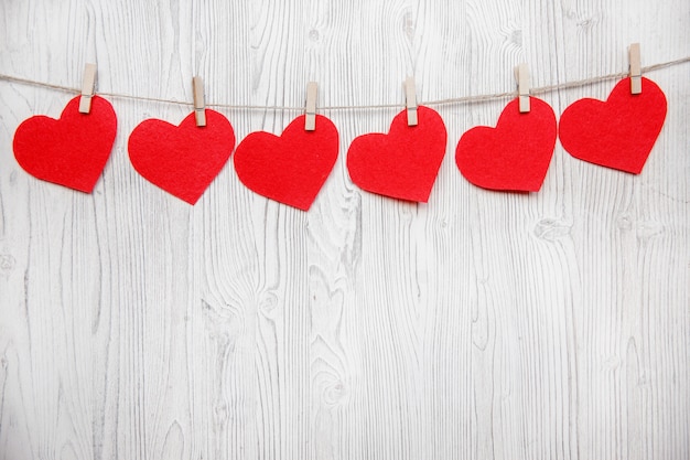 Fondo de San Valentín con borde de fila de corazones rojos en pinzas para la ropa en madera blanca. Lugar para el texto, lugar para copiar.
