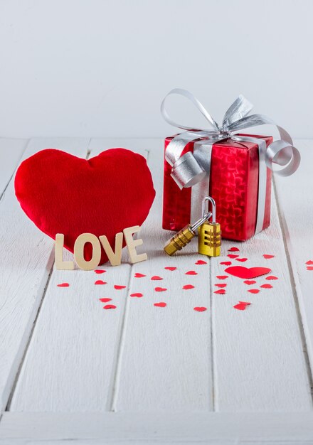 Fondo de San Valentín con caja de regalo roja, forma de corazón y candado de combinación de pareja en blanco