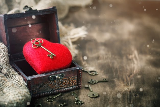 Fondo de San Valentín con un corazón y una antigua llave en mesa de madera.