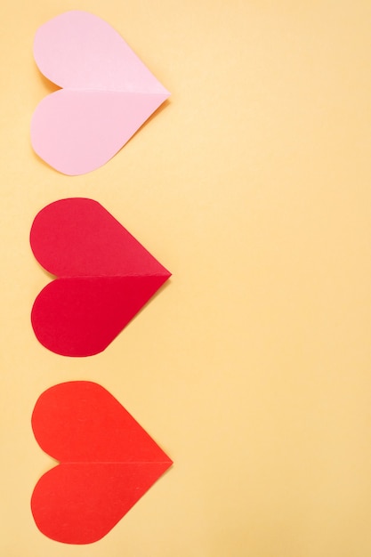 Fondo de San Valentín. Corazones rosados y rojos sobre un fondo amarillo pastel. Concepto de San Valentín. Endecha plana, vista superior, espacio de copia