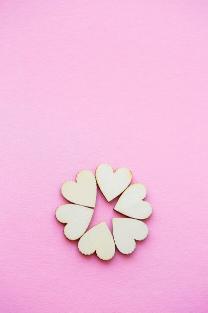 Fondo de San Valentín. fila de corazones de madera sobre un fondo rosa. Concepto de San Valentín. Vista superior, lugar para una inscripción, publicidad.