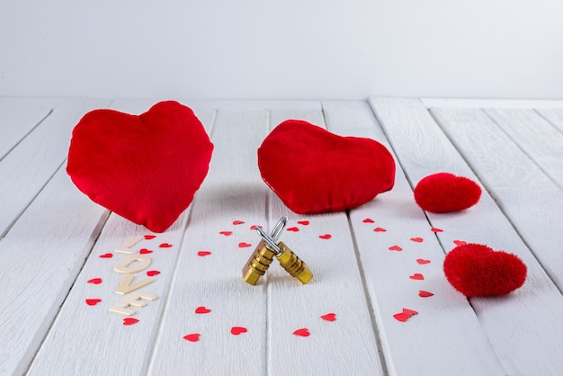 Fondo de San Valentín con forma de corazón rojo y candado de combinación de pareja en mesa de madera blanca