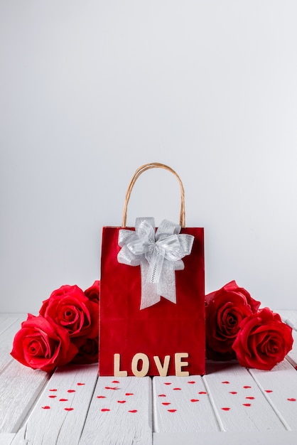 Fondo de San Valentín con rosa roja, forma de corazón, bolsa de regalo, palabra de letras de madera