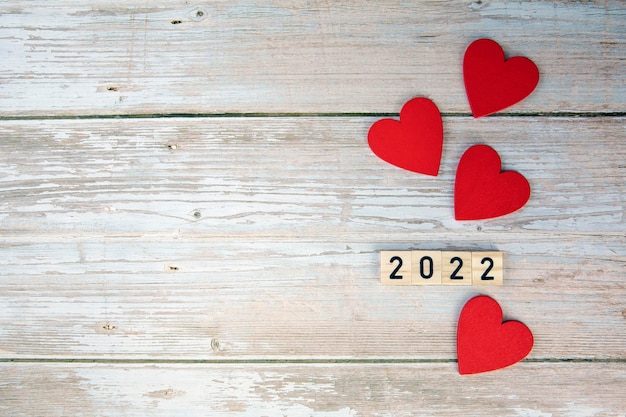 Fondo de símbolo del día de San Valentín 2022 Año y corazones rojos sobre fondo de madera diseño romántico