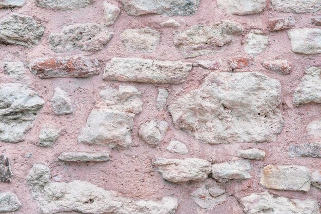 El fondo de la superficie de la pared está hecho de arcilla rosa y piedras calizas ásperas blancas