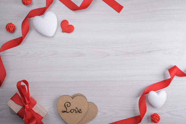 Fondo para la tarjeta de felicitación del día de San Valentín. Concepto del día de San Valentín. Cintas de regalo rojas, regalos, corazones sobre un fondo de madera. Vista superior.