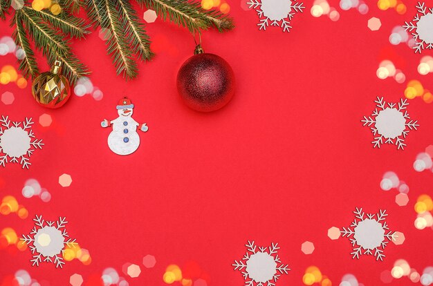 Fondo de tarjeta de felicitación de feliz Navidad con un muñeco de nieve, ramas de árboles de Navidad y bolas con un marco de bokeh.