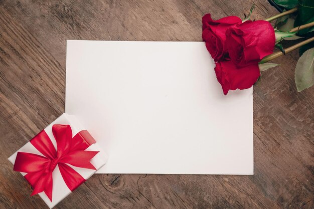 Fondo de la tarjeta de felicitación de San Valentín con caja de regalos y rosas borgoñonas frescas