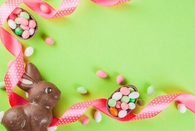 Fondo de tarjeta de felicitación de vacaciones de Pascua, con conejito de pascua de chocolate, huevos de caramelo, huevos de codorniz y cinta festiva