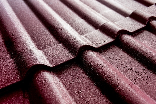 Fondo de tejas metálicas rojas con gotas de agua.