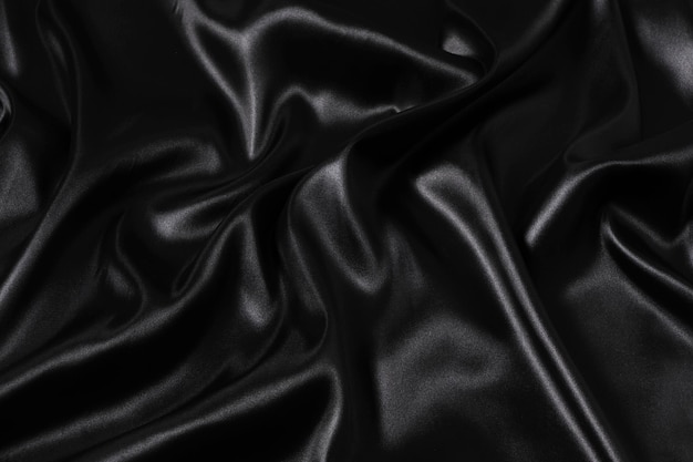Fondo de tela de satén negro ondulado abstracto de tela de seda