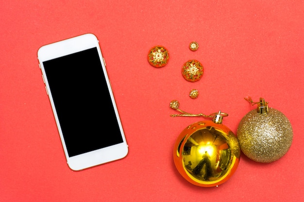 Fondo de teléfono inteligente de Navidad o año nuevo: ramas de abeto, bolas de cristal de oro, decoración y conos sobre un fondo rojo