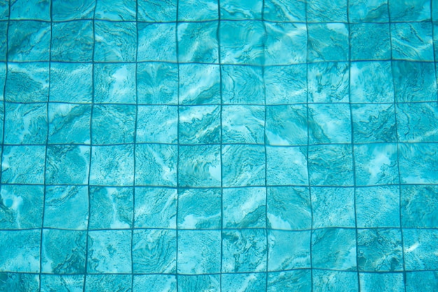 Fondo y textura de agua en la piscina con azulejos azules.