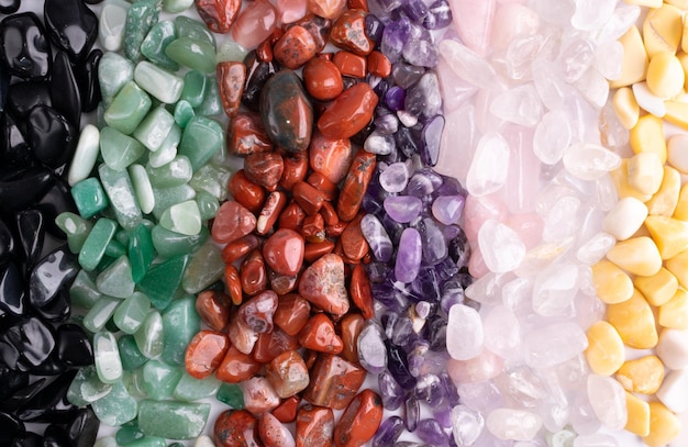 Fondo de textura de piedras de colores. Guijarros de cuarzo verde, rojo, azul, blanco, negro y morado mezclan vista superior