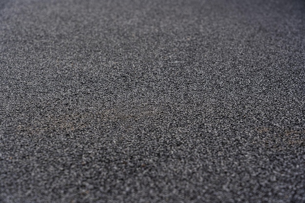 Fondo de textura de piso de caucho negro. Recubrimiento de migas de caucho negro en el campo deportivo. enfoque selectivo