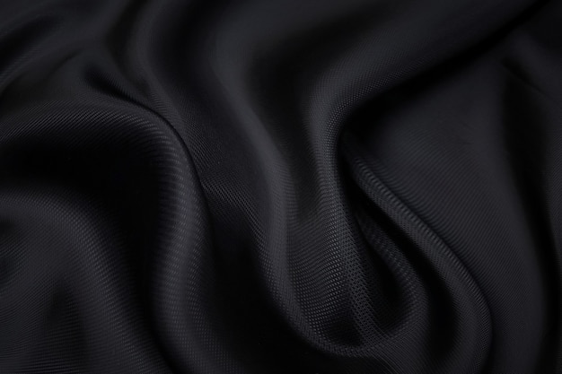 Fondo de textura de tela negra, tela ondulada de color negro resbaladizo, textura de tela de satén o seda o lana de lujo.
