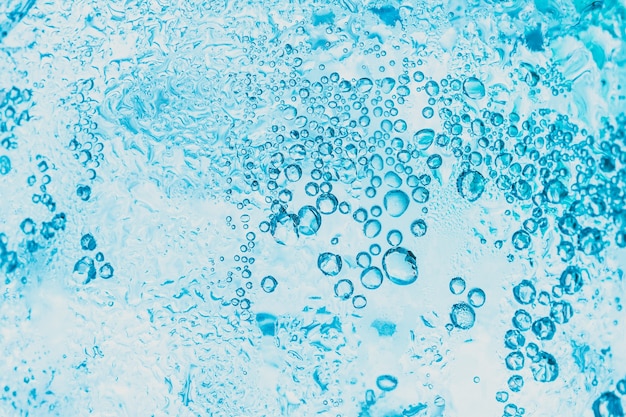 Fondo transparente de agua de soda y hielo con burbujas azules brillantes dentro del vidrio es abstracto.