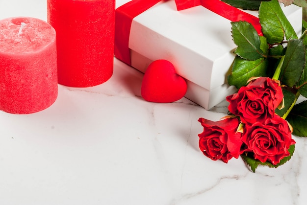 Fondo de vacaciones, día de San Valentín. Ramo de rosas rojas, corbata con una cinta roja, con caja de regalo envuelta. En la mesa de mármol blanco