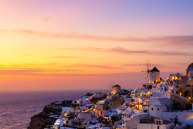 Fondo de vacaciones en Grecia Famoso pueblo icónico de Oia con casas blancas tradicionales y molinos de viento durante la colorida puesta de sol Isla de Santorini Grecia