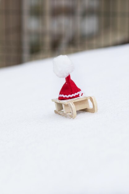 Fondo de vacaciones de invierno: sombrero de Santa Claus en un trineo de madera. De cerca