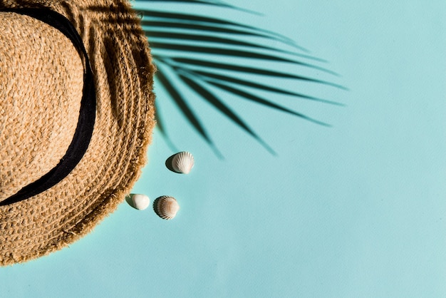 Fondo de vacaciones en el mar sombrero de paja y conchas sobre fondo de color azul