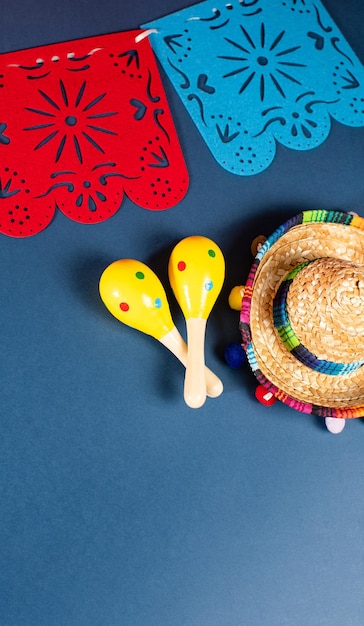 Fondo de vacaciones mexicanas Guirlandas de papel que decoran Sombrero y maracas sobre fondo azul