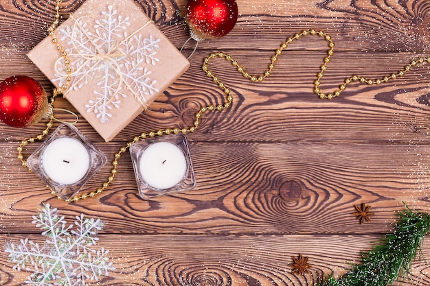 Fondo de vacaciones de Navidad y año nuevo. Decoración con regalos envueltos en papel kraft, velas, adornos navideños, abalorios, copos de nieve, sobre una mesa de madera. Lay Flat, espacio vacío