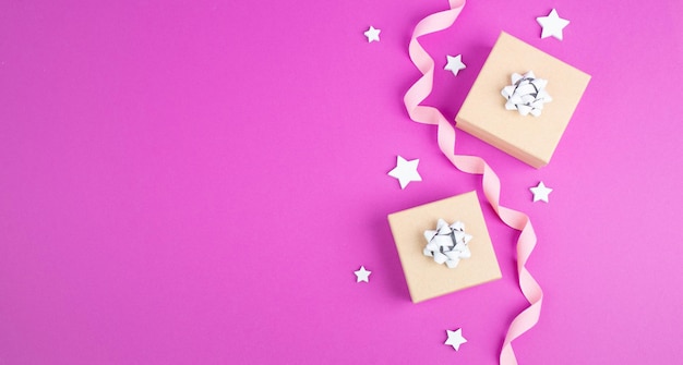 Fondo de vacaciones de Navidad con pequeñas cajas de regalo, estrellas y ramas de abeto, fondo rosa de moda