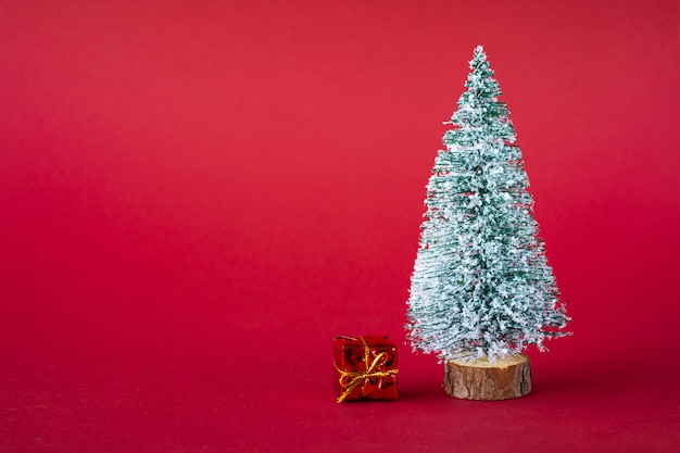 Fondo de vacaciones de Navidad. Árbol de Navidad cubierto de nieve y cajas multicolores brillantes con regalos. Copie el espacio.