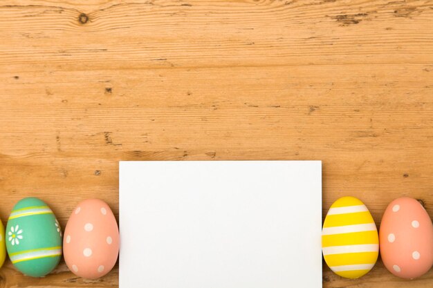 Fondo de vacaciones de Pascua Huevos de Pascua decorados en colores pastel con una etiqueta blanca en blanco sobre un fondo de madera