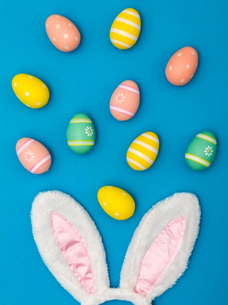 Fondo de vacaciones de Pascua con orejas de conejo y huevos de Pascua sobre un fondo azul