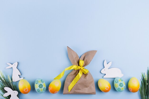 Fondo de vacaciones de Pascua Vista superior de coloridos huevos de gallina pintados en una fila y paquete de papel artesanal en forma de conejito