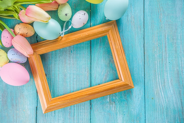 Fondo de vacaciones de primavera y Pascua con flores de tulipán, huevos de colores pastel en la vista superior de la mesa azul. Tarjeta de felicitación de Pascua feliz.