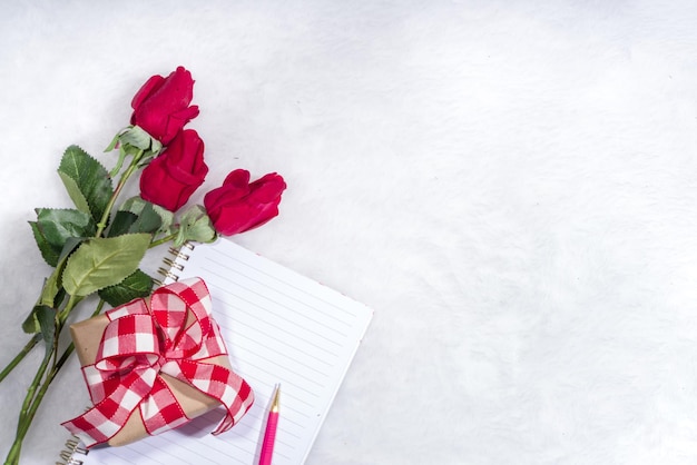 Fondo de vacaciones de San Valentín. Caja de regalo de papel artesanal con cinta, flores rosas y decoración de corazones, espacio de copia