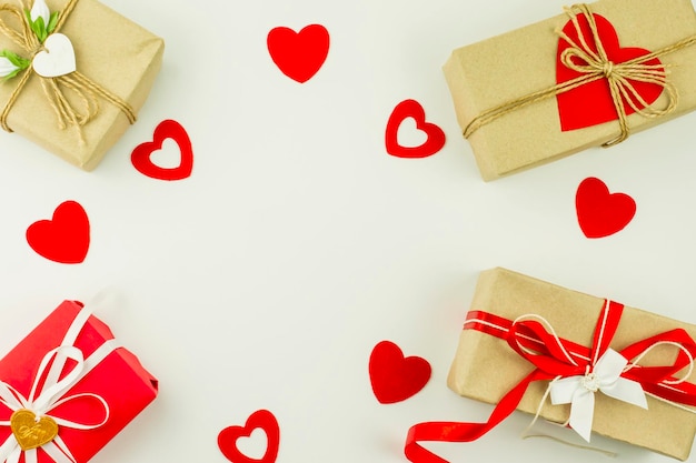 Fondo de vacaciones de San Valentín. cajas de regalo en papel artesanal, decoradas con corazones de colores y corazones rojos sobre fondo blanco. vista superior. endecha plana.