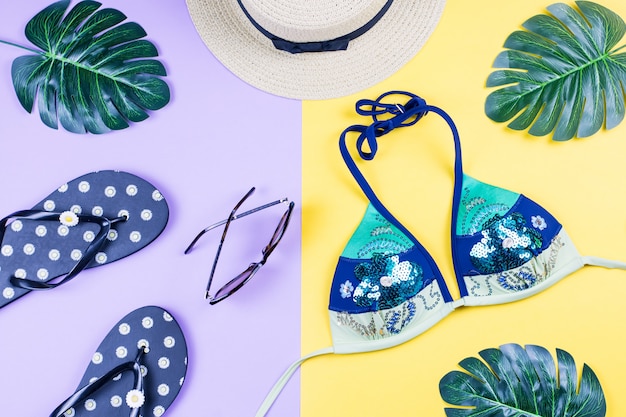 Fondo de vacaciones de verano. Concepto de verano tropical con accesorios de moda, bikini, hojas sobre fondo brillante.