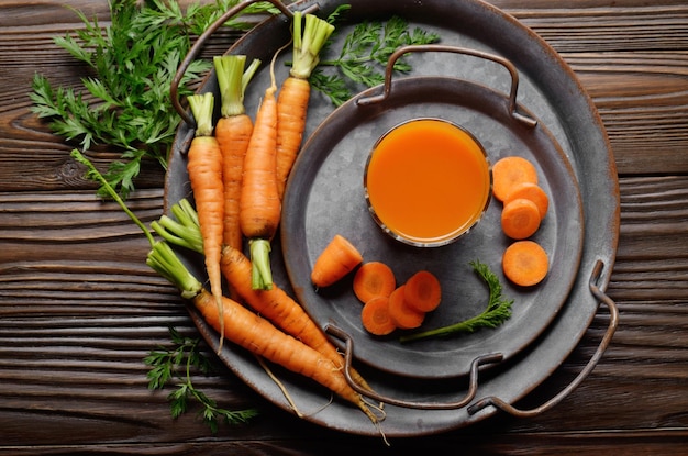 Fondo vegetariano de bandeja antigua con zanahorias orgánicas frescas y jugo en la mesa de madera de la cocina Vista superior