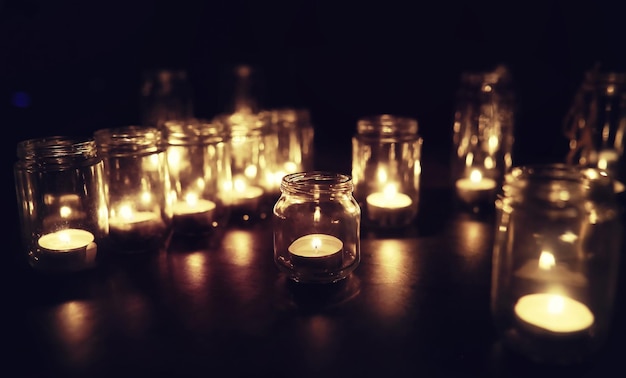 Fondo con velas en recipientes de vidrio Las velas arden en un lugar oscuro Descanse en paz