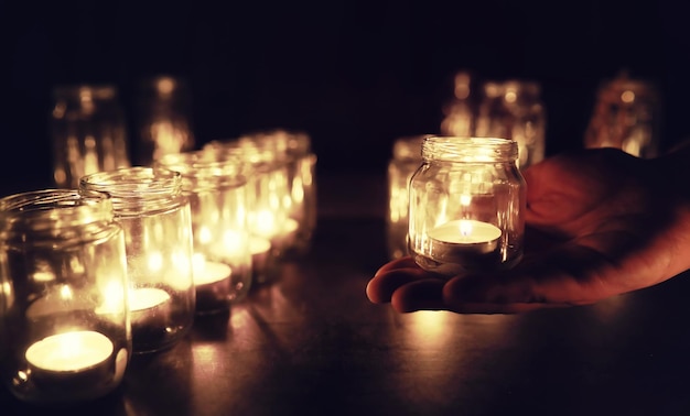 Fondo con velas en recipientes de vidrio. Las velas se queman en un lugar oscuro. Descansa en paz.