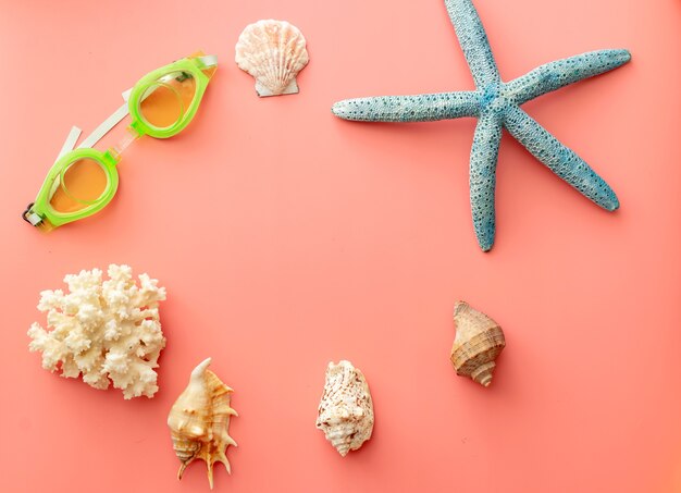 Fondo de verano de estrellas de mar, gafas de natación, conchas, coral sobre fondo rosa