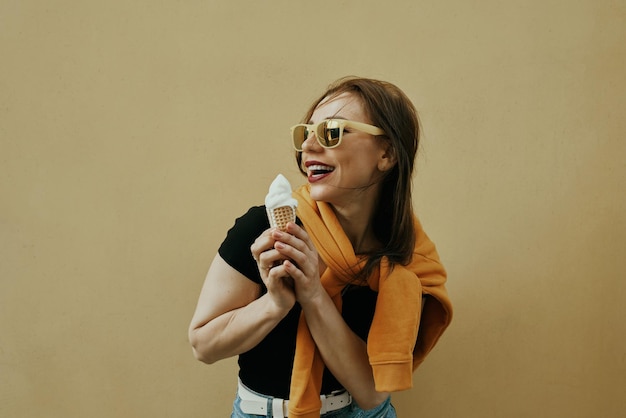 Foto fondo de verano. hermosa joven come helado. fondo de color. ubicación de la ciudad