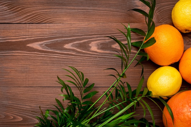 Fondo de verano de limones, naranjas y palmeras sobre superficie de madera