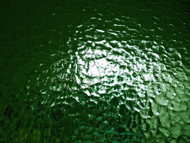 Fondo verde de vidrio corrugado Patrón abstracto en la superficie de una ventana Película protectora opaca