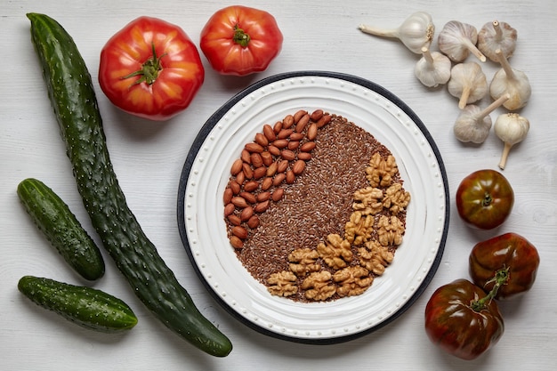 Un fondo de verduras frescas sobre una mesa de madera y con un plato de nueces