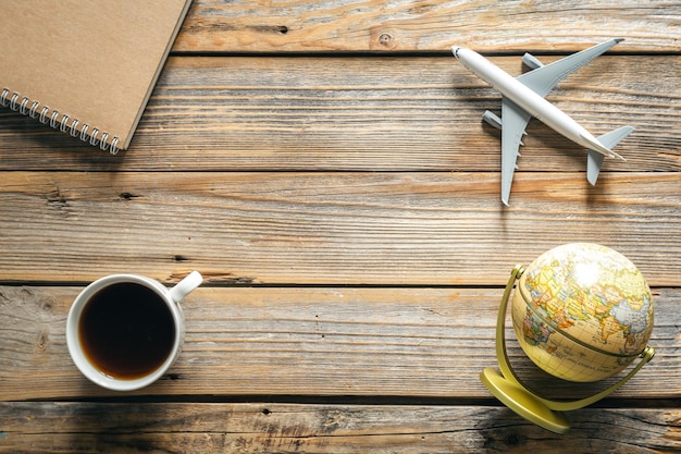 Fondo de viaje con taza de café de globo de bloc de notas y vista superior del modelo de avión