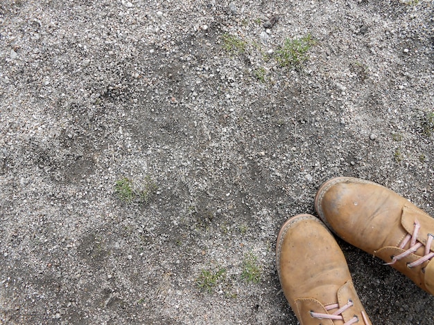 fondo viejo y gastado piso de arena con dos botas de trabajo en la esquina