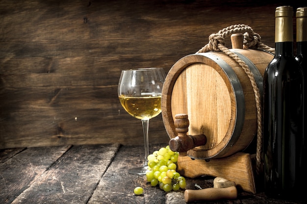 Fondo de vino. Un barril de vino blanco con ramas de uvas verdes.