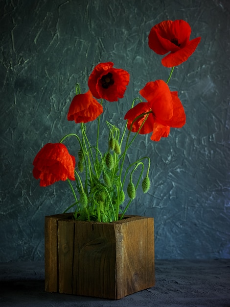 Fondo vintage con amapolas rojas en un florero de madera