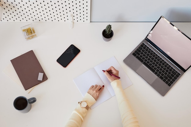 Fondo de vista superior de mujer usando laptop con pantalla en blanco en el espacio de copia de lugar de trabajo blanco